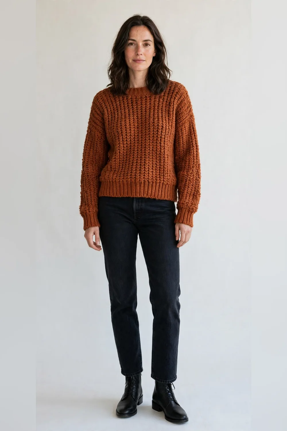 Rust chunky knit sweater with dark straight jeans and black ankle boots for women in their 30s