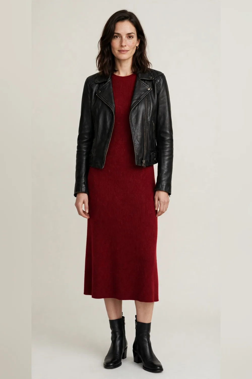 Black leather jacket over a red knit midi dress with black ankle boots for women in their 30s