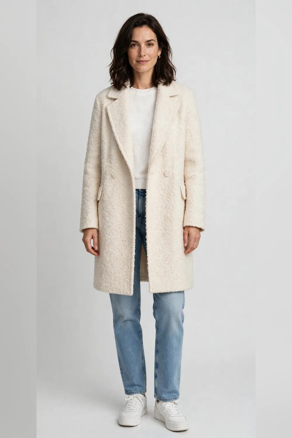 Cream bouclé coat with light wash straight jeans and white trainers for women in their 30s